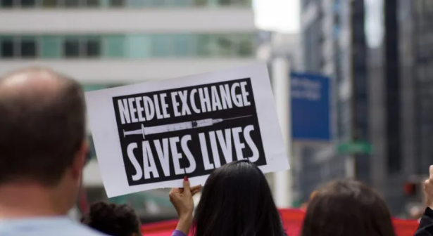 Sign reading "Needle Exchange Saves Lives"